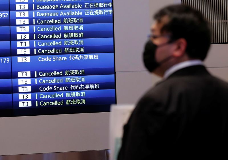 © Reuters. A man stands in front of a monitor showing flight schedules at an arrival hall of Haneda airport's international terminal, amid the coronavirus disease (COVID-19) outbreak, in Tokyo, Japan, November 29, 2021. REUTERS/Kim Kyung-Hoon