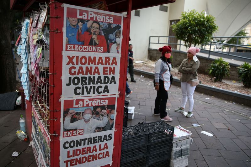 © Reuters. People stand by a newspaper stand that displays cover stories on the preliminary results of the general election in Tegucigalpa, Honduras, November 29, 2021. REUTERS/Jose Cabezas