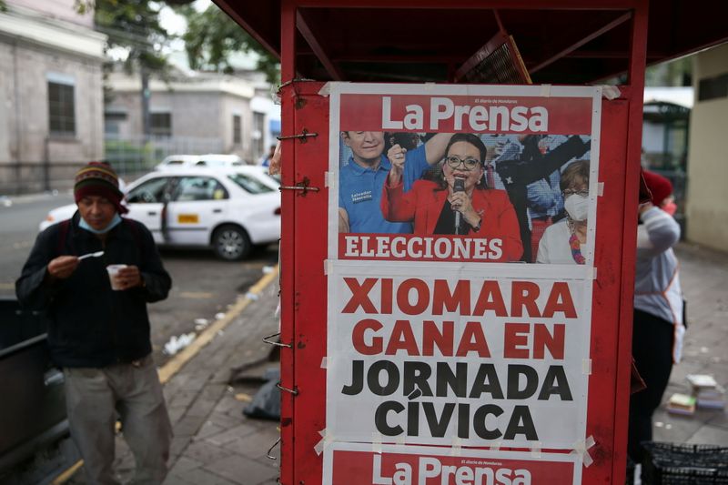 &copy; Reuters. A man eats by a newspaper stand that displays a cover story on the preliminary results of the general election in Tegucigalpa, Honduras, November 29, 2021. REUTERS/Jose Cabezas