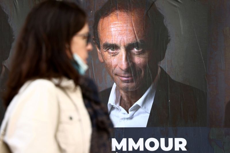 &copy; Reuters. FILE PHOTO: A woman walks past posters in support of French far-right commentator Eric Zemmour, probable candidate for the French presidential election next April, posted on a wall in Paris, France, October 13, 2021. Picture taken October 13, 2021. REUTER