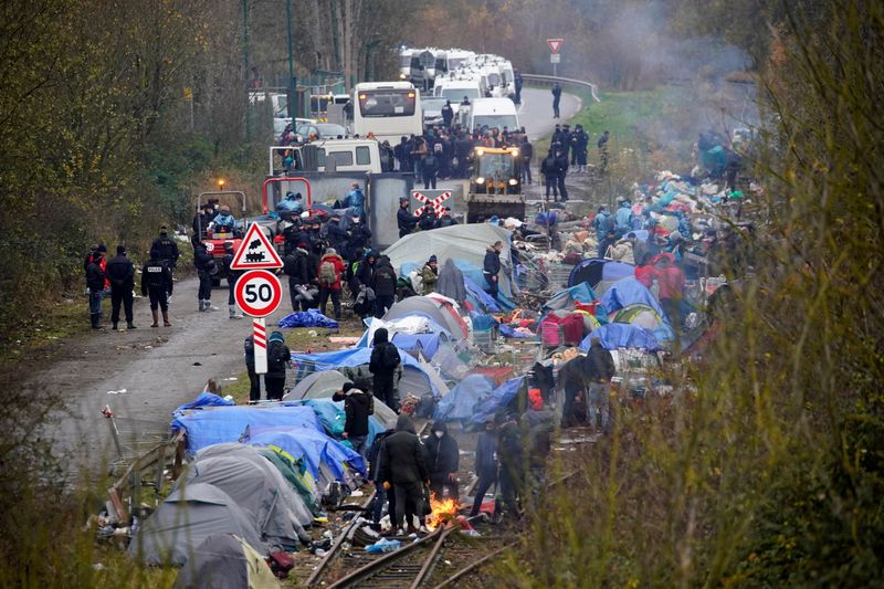 &copy; Reuters. Los inmigrantes se reúnen mientras los policías franceses desmantelan su campamento improvisado en la playa de Loon, cerca de Dunkerque, Francia, 30 de noviembre de 2021. REUTERS/Juan Medina