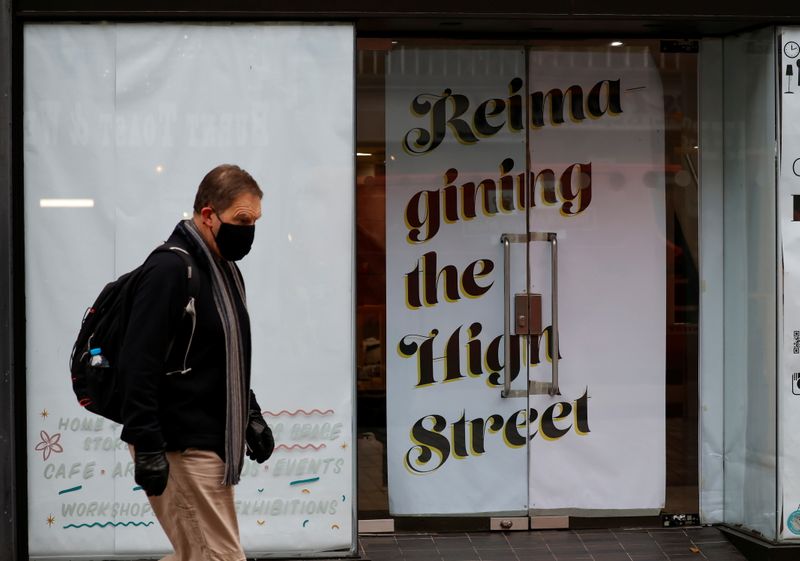 &copy; Reuters. FOTO DE ARCHIVO: Un hombre con mascarilla pasa por delante de un local comercial cerrado en el centro de Chester, el Reino Unido, el 26 de octubre de 2021. REUTERS/Phil Noble