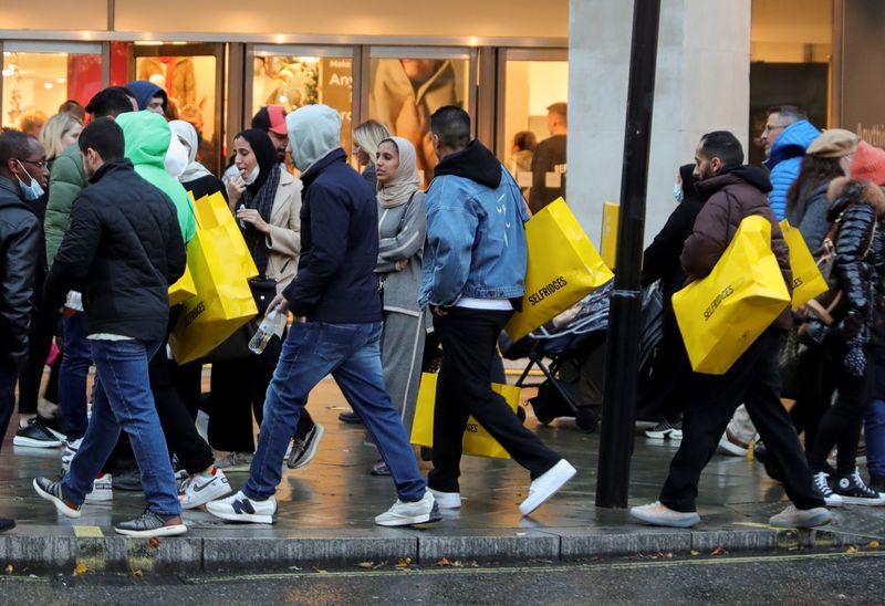 &copy; Reuters. FILE PHOTO: Pedestrians walk with shopping bags on "Black Friday" in the West End shopping district of London, Britain, November 26, 2021. REUTERS/May James