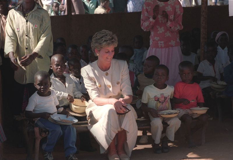 © Reuters. صورة من أرشيف رويترز للأميرة ديانا تجلس بين أطفال مدرسة بجنوب شرق زيمبابوي.