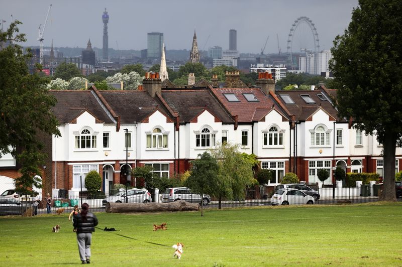 © Reuters. FILE PHOTO: A person walks with a dog in front of a row of residential housing in south London, Britain, August 6, 2021. REUTERS/Henry Nicholls/File Photo