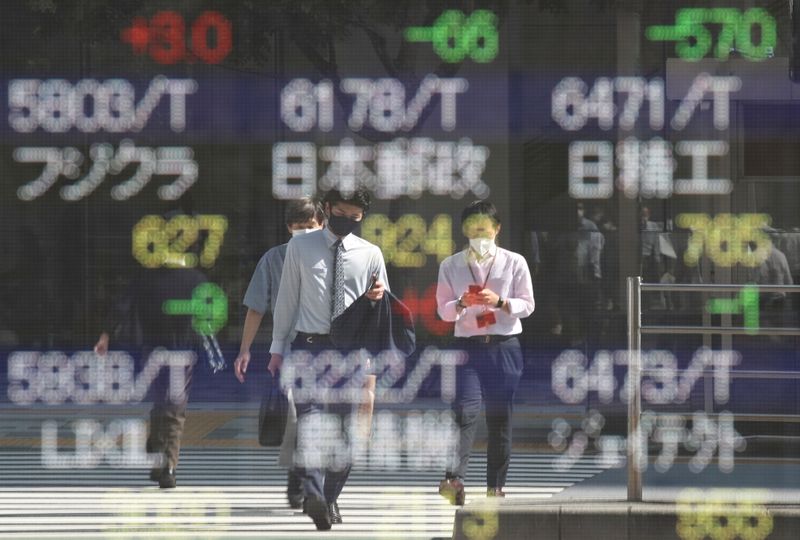 © Reuters. People wearing protective masks, amid the coronavirus disease (COVID-19) outbreak, are reflected on an electronic board displaying Japan's stock prices outside a brokerage in Tokyo, Japan, October 5, 2021. REUTERS/Kim Kyung-Hoon