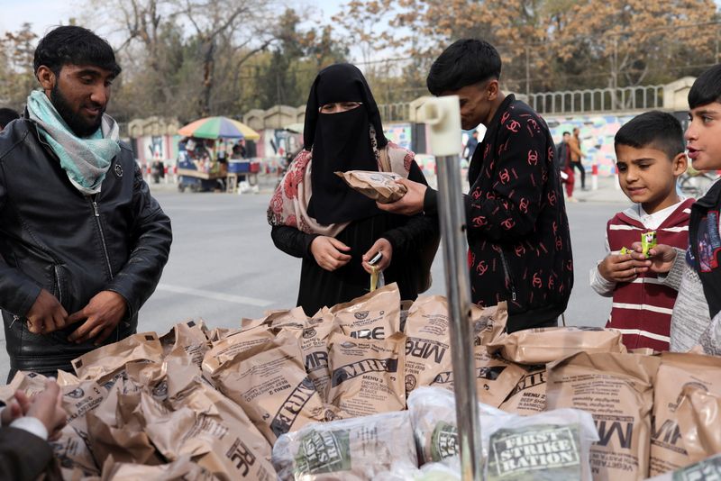 &copy; Reuters. امرأة أفغانية تشتري طعاما تركته القوات الأمريكية من بائع متجول في كابول يوم 17 نوفمبر تشرين الثاني 2021. تصوير: عمر خارا - رويترز. 
