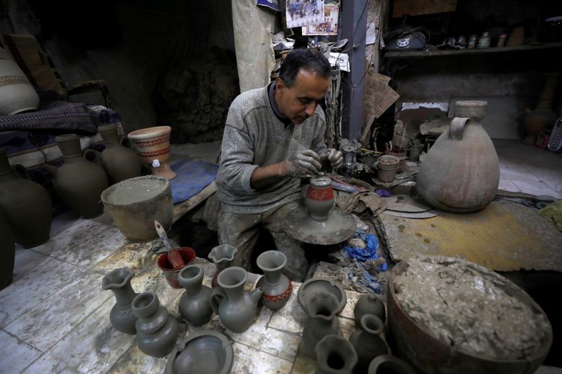 © Reuters. الفلسطيني جمال الفاخوري يصنع مزهرية من الفخار في مصنع بقبو صغير‭‭‭‭‭‭ ‬‬‬‬‬‬قرب جنين بالضفة الغربية المحتلة يوم 28 نوفمبر تشرين الثاني 2021. تصوير: محمد تركمان - رويترز.  

