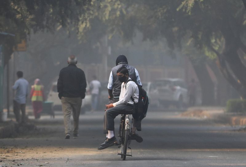 &copy; Reuters. رجل يقود دراجة وخلفه صبي أثناء توصيله إلى المدرسة في نيودلهي يوم 29 نوفمبر تشرين الثاني 2021 بعد انقطاع دام نحو 15 يوما نتيجة لتلوث الهواء. تصوير