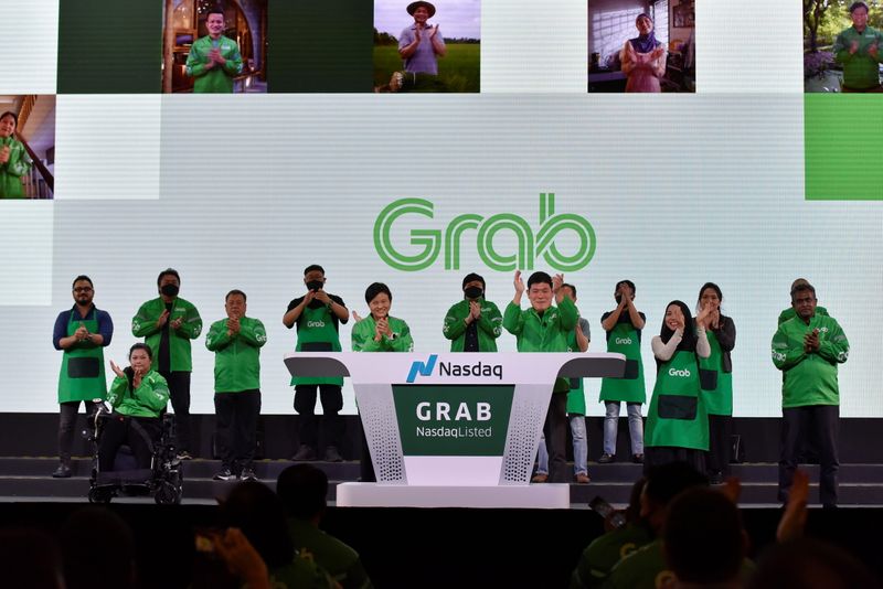 © Reuters. Grab's CEO Anthony Tan and co-founder Tan Hooi Ling clap hands as they attend the Grab Bell Ringing Ceremony at a hotel in Singapore, December 2, 2021. REUTERS/Caroline Chia