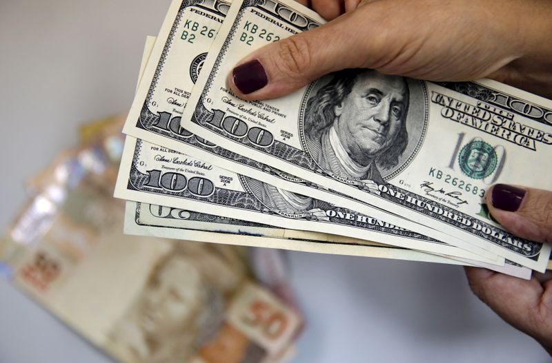 &copy; Reuters. Mulher segura notas de dólar com cédulas de reais ao fundo. Rio de Janeiro, Brasil. 31 de março de 2015. REUTERS/Sergio Moraes