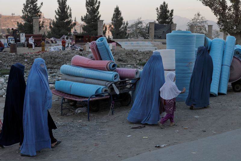 &copy; Reuters. Women wearing burqas walk in a second-hand market where people sell their home appliances and other belongings, in Kabul, Afghanistan October 9, 2021. REUTERS/Jorge Silva