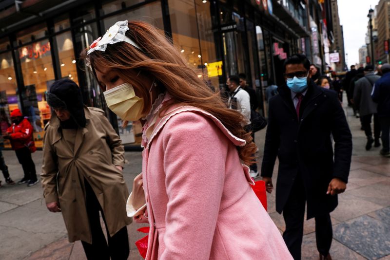&copy; Reuters. FILE PHOTO: A woman wearing a protective face mask, amid the coronavirus disease (COVID-19) pandemic, walks by pedestrians along 34th street outside Pennsylvania Station in New York City, U.S., November 22, 2021.  REUTERS/Shannon Stapleton