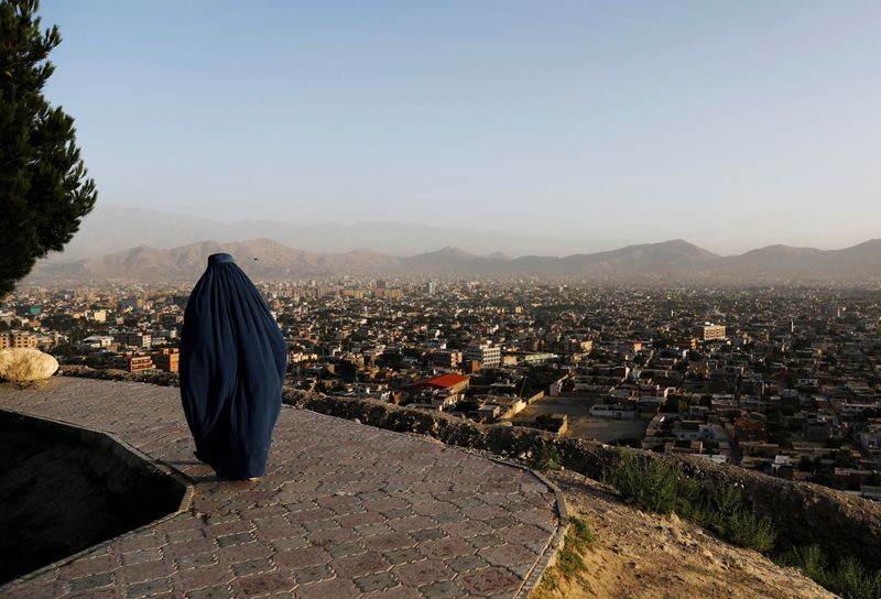 &copy; Reuters. أفغانية  تسير قرب تلة مشرفة على منظر عام للعاصمة كابول في صورة من أرشيف رويترز.