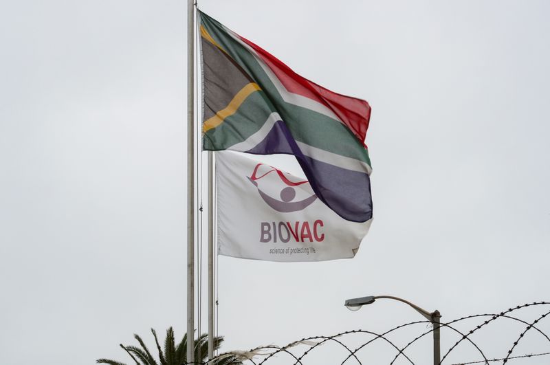 &copy; Reuters. FOTO DE ARCHIVO-Una bandera sudafricana ondea junto a una con el logotipo de la empresa local de fabricación y almacenamiento de vacunas Biovac, frente a las oficinas de la compañía en Ciudad del Cabo, Sudáfrica. 18 de marzo de 2021. REUTERS/Mike Hutc