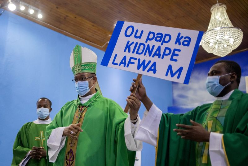 &copy; Reuters. FILE PHOTO: Max Leroy Mesidor, the Metropolitan Archbishop of Port-au-Prince, hands off a placard that reads "You cannot kidnap my faith", which he received as an offering from worshippers during Sunday Catholic Mass at the Chapelle de l'Immaculee Concept
