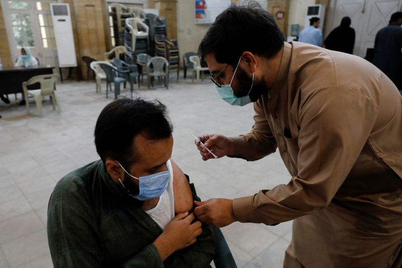 &copy; Reuters. رجل يتلقى جرعة من اللقاح الواقي من الإصابة بفيروس كورونا في مركز تطعيم بكراتشي يوم الاثنين. تصوير: أخطر سومرو - رويترز
