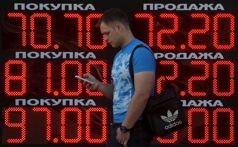 &copy; Reuters. FILE PHOTO: A man uses his mobile phone while walking past a board showing currency exchange rates of the U.S. dollar, euro and British pound (top-bottom) against Russian rouble in Moscow, Russia, August 24, 2015. REUTERS/Sergei Karpukhin