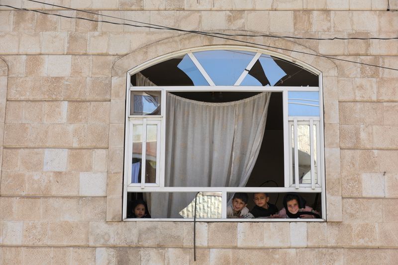 &copy; Reuters. Unos niños miran desde la ventana de su apartamento en un edificio cercano a un taller de coches alcanzado por un ataque aéreo liderado por Arabia Saudí, en Saná, Yemen 7 de diciembre de 2021. REUTERS/Khaled Abdullah