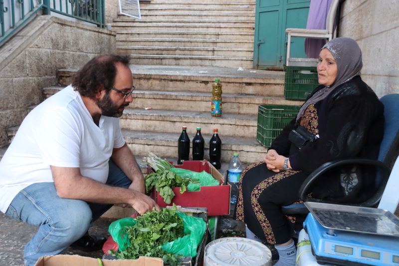 &copy; Reuters. El chef palestino Fadi Kattan habla con una vendedora de hierbas palestina, en Belén, en la Cisjordania ocupada por Israel. 17 de noviembre de 2021. REUTERS/Zainah El-Haroun 