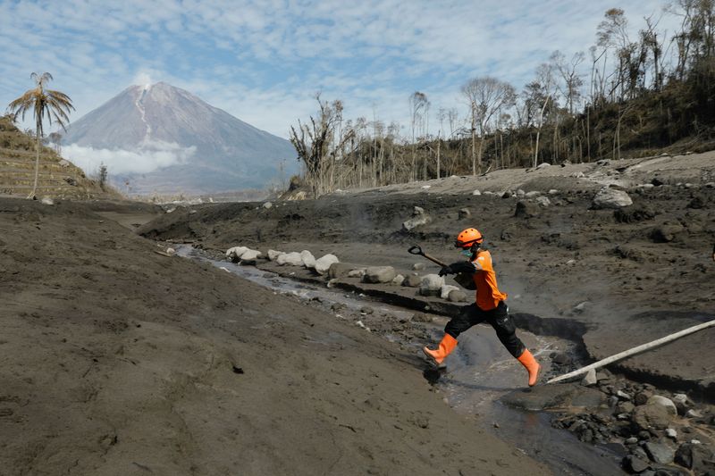 © Reuters. A rescue worked jumps across the lava flow path during an operation at an area affected by the eruption of Mount Semeru volcano, in Curah Kobokan, Pronojiwo district, Lumajang, East Java province, Indonesia, December 8, 2021. REUTERS/Willy Kurniawan