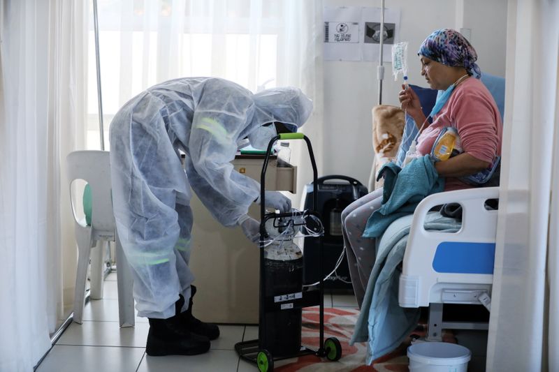 &copy; Reuters. FILE PHOTO: A healthcare worker assists a patient being treated at a makeshift hospital run by charity organisation The Gift of the Givers, during the coronavirus disease (COVID-19) outbreak in Johannesburg, South Africa, July 11, 2021. REUTERS/ Sumaya Hi