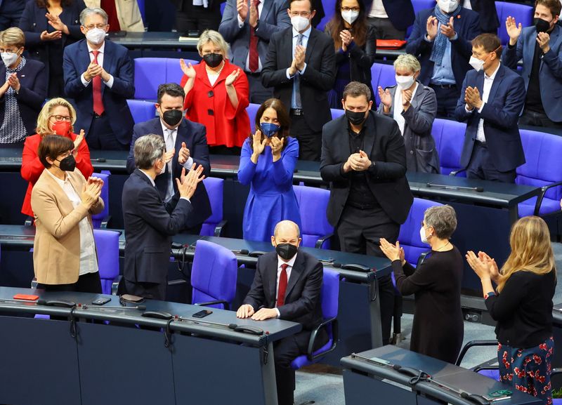 &copy; Reuters. ドイツ下院は８日、社会民主党（ＳＰＤ）のオラフ・ショルツ氏（６３）を新首相に選出した。拍手を受けるショルツ氏（中央）。（２０２１年　ロイター/Fabrizio Bensch）