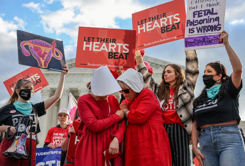 © Reuters. FILE PHOTO: Women dressed as handmaids demonstrate in front of anti-abortion protestors outside the United States Supreme Court as the court hears arguments over a challenge to a Texas law that bans abortion after six weeks in Washington, U.S., November 1, 2021. REUTERS/Evelyn Hockstein