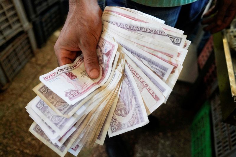 &copy; Reuters. FILE PHOTO: A vendor shows Cuban pesos notes in a public market in Havana, Cuba, June 12, 2021. REUTERS/Alexandre Meneghini