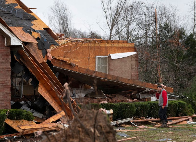 &copy; Reuters. Braden McCann uses his phone and surveys the damage as he stands outside his home after devastating outbreak of tornadoes ripped through several U.S. states, in Dickson, Tennessee, U.S., Decemeber 11, 2021.  George Walker IV/The Tennessean/USA TODAY via R