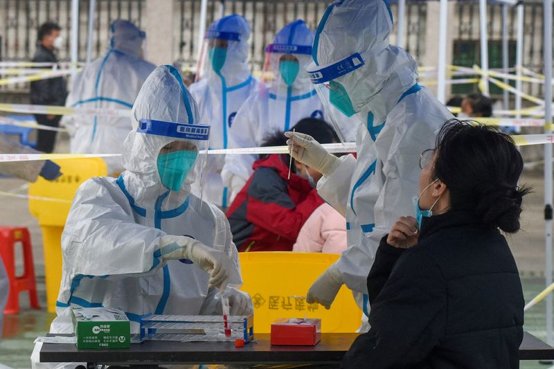 &copy; Reuters. Trabajadores médicos con trajes de protección recogen hisopos de los residentes en un sitio de pruebas de ácido nucleico durante una tercera ronda de pruebas masivas para la enfermedad del coronavirus (COVID-19) en el distrito de Zhenhai de Ningbo, pro