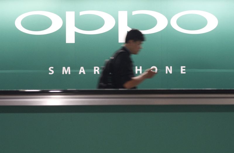 &copy; Reuters. FILE PHOTO: A commuter using his mobile phone passes an advertisement of Chinese smartphone maker Oppo at a train station in Singapore May 8, 2014.  REUTERS/Edgar Su 