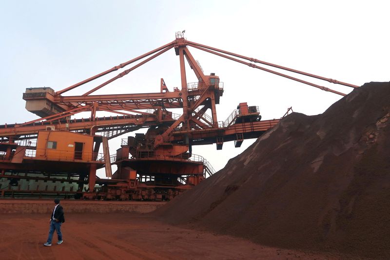 © Reuters. FILE PHOTO: A man walks by an iron ore blending site at Dalian Port, Liaoning province, China September 21, 2018. Picture taken September 21, 2018. REUTERS/Muyu Xu/File Photo