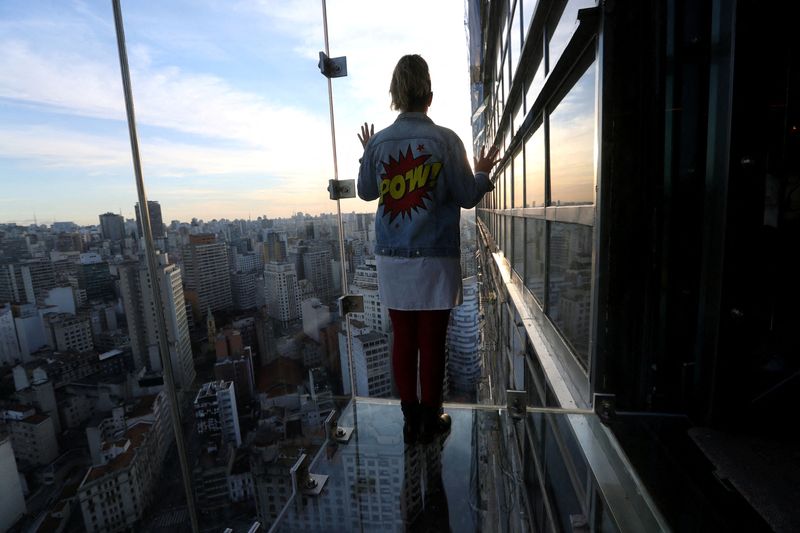 © Reuters. FILE PHOTO: Influencer Renata Tellers looks out of the Sampa Sky, a reinforced glass box that protrudes beyond the building and allows to see not only the horizon, but also the ground below your feet, in downtown Sao Paulo, Brazil, August 3, 2021. REUTERS/Amanda Perobelli//File Photo