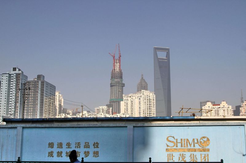 &copy; Reuters. FILE PHOTO: A man walks past a wall carrying the logo of Shimao Group, with residential buildings and the financial district of Pudong seen in the background, in Shanghai, China January 1, 2013. REUTERS/Stringer