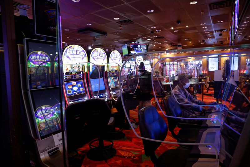 © Reuters. FILE PHOTO: People sit wearing protective face masks, amid the coronavirus disease (COVID-19) pandemic, behind plastic barriers playing slot machines at the Ute Mountain Hotel and Casino in Towaoc, Colorado, U.S., December 15, 2021.  REUTERS/Shannon Stapleton