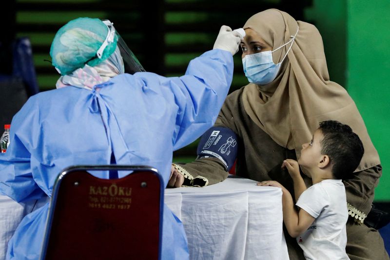 &copy; Reuters. FILE PHOTO: A woman undergoes a health screening before receiving a dose of a vaccine against the coronavirus disease (COVID-19) during a mass vaccination program for asylum seekers and refugees at a sports hall in Jakarta, Indonesia, October 7, 2021. REU