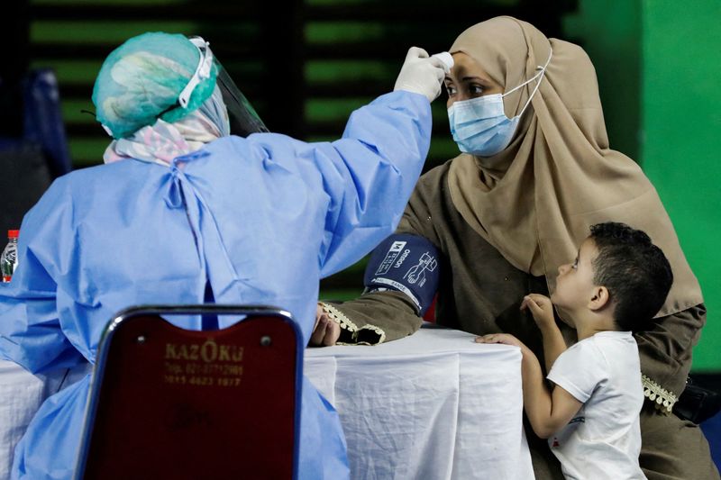 &copy; Reuters. امرأة تخضع للفحص قبل تلقي جرعة من لقاح للوقاية من كوفيد-19 خلال حملة تطعيم جماعية لطالبي اللجوء في مجمع رياضي بالعاصمة الإندونيسية جاكرتا في 
