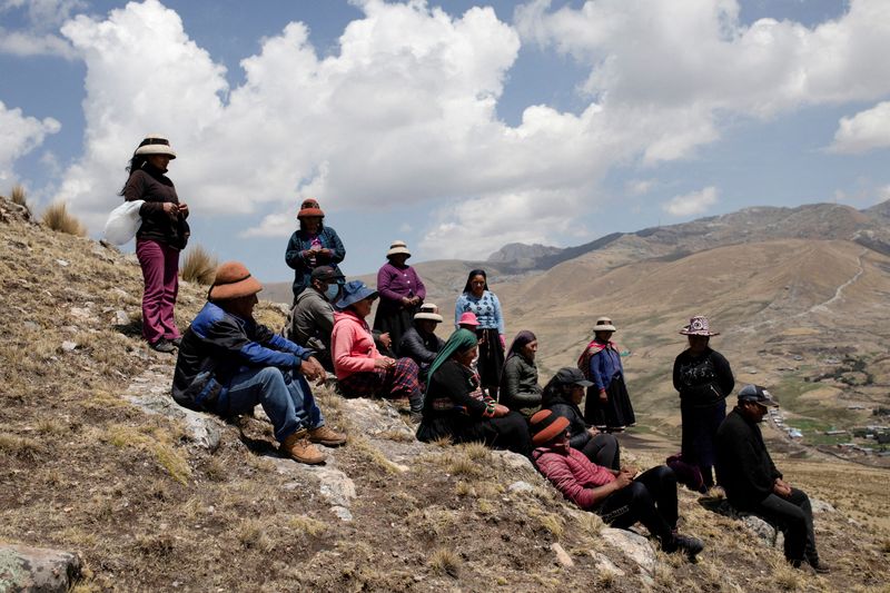 © Reuters. FILE PHOTO: People sit in the mountains in front of a mine operated by MMG Las Bambas, in a region where locals claim mining activity has negatively affected crop yields and killed livestock, outside of Cusco, Peru October 14, 2021. REUTERS/Angela Ponce