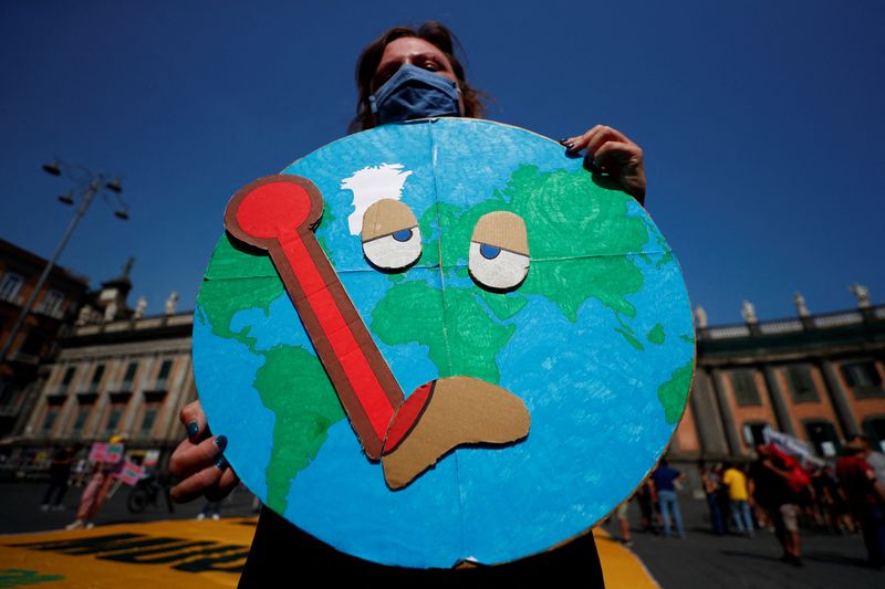 © Reuters. FILE PHOTO: A person holds a placard as climate activists including Extinction Rebellion and Fridays for Future stage a protest demanding more action whilst G20 climate and environment ministers hold a meeting in Naples, Italy, July 22, 2021. REUTERS/Guglielmo Mangiapane/File Photo