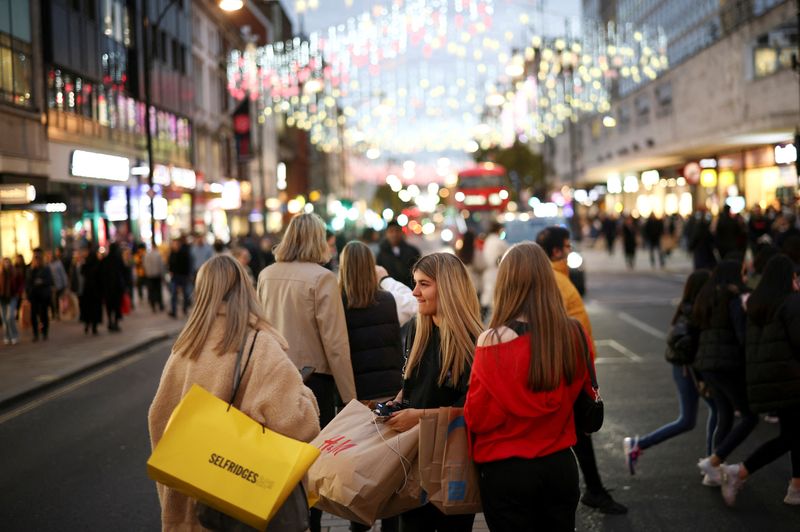 © Reuters. FILE PHOTO: People with shopping bags walk along Oxford Street illuminated with Christmas lights in London, Britain, November 13, 2021. REUTERS/Henry Nicholls/File Photo