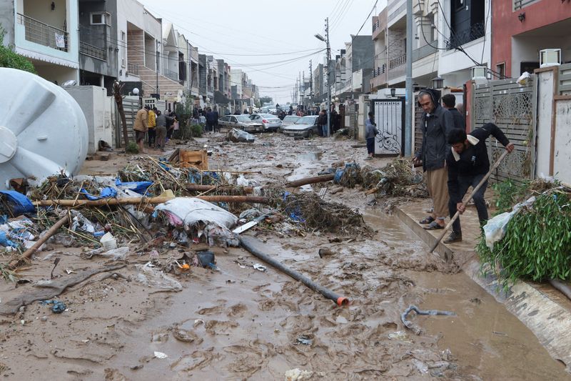 &copy; Reuters. سكان يحاولون تنظيف الحطام من طريق اجتاحته مياه السيول والطين في أربيل بالعراق يوم الجمعة. تصوير أزاد لاشكاري- رويترز.