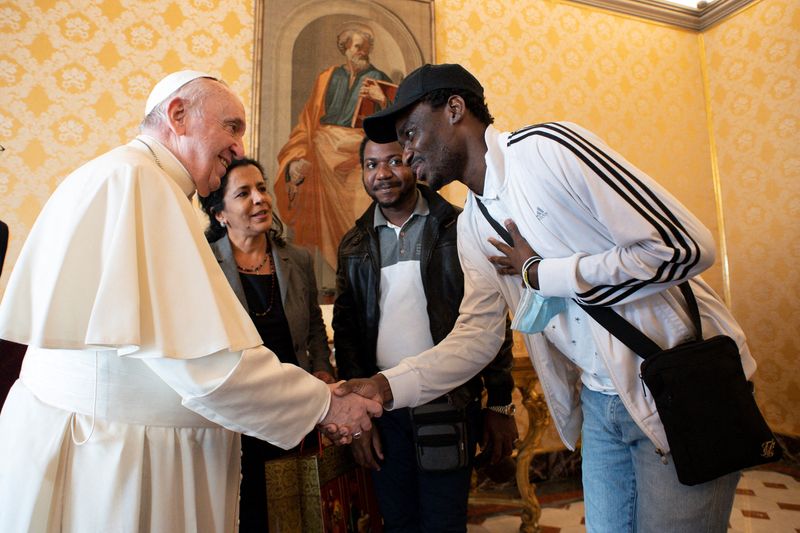 &copy; Reuters. البابا فرنسيس يصافح أحد المهاجرين في الفاتيكان يوم الجمعة. صورة من المكتب الإعلامي للفاتيكان.