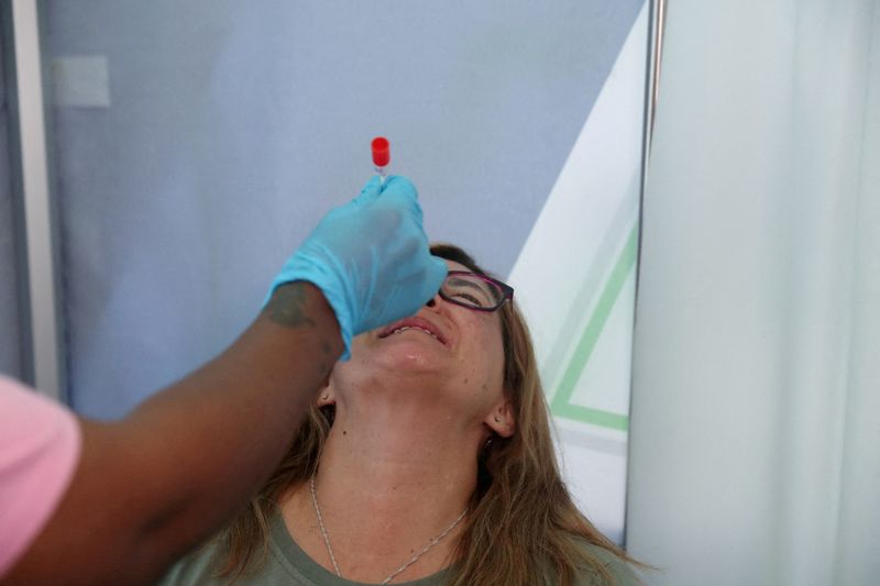 &copy; Reuters. FILE PHOTO: A healthcare worker collects a swab from Bronwen Cook for a PCR test against the coronavirus disease (COVID-19) before traveling to London, at O.R. Tambo International Airport in Johannesburg, South Africa, November 26, 2021. REUTERS/ Sumaya H