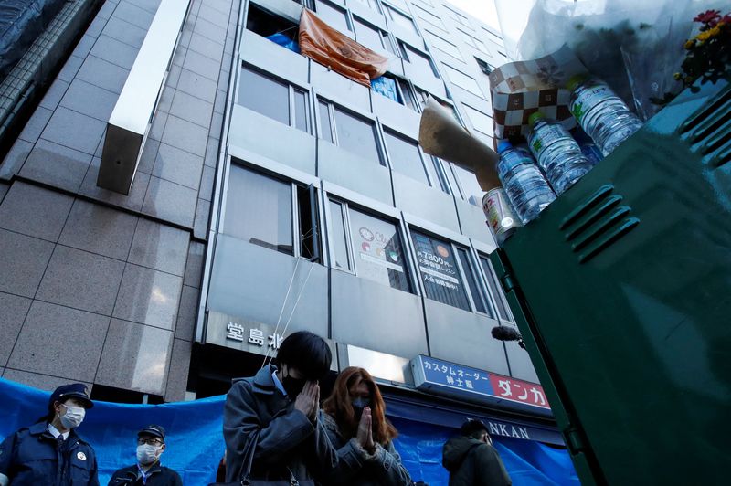 © Reuters. معزون يؤدون الصلوات على أرواح ضحايا حريق بعيادة للطب النفسي وذلك أمام المبنى الذي يضم العيادة في مدينة أوساكا اليابانية يوم السبت. تصوير:رويترز.