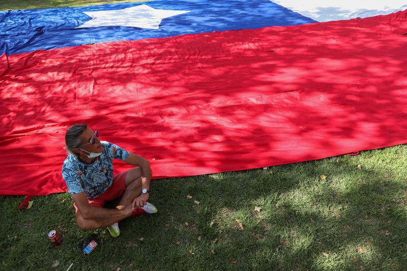 &copy; Reuters. Foto del miércoles de un hombre junto a una bandera chilena en uno de los actos de cierre de campaña de los candidatos a la elección presidencial del domingo en Chile. 
Dic 16, 2021. REUTERS/Ivan Alvarado
