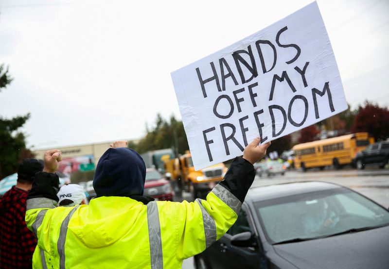 © Reuters. FILE PHOTO: A protester gestures at passing traffic as Boeing employees and others line the street to protest the company's coronavirus disease (COVID-19) vaccine mandate, outside the Boeing facility in Everett, Washington, October 15, 2021.  REUTERS/Lindsey Wasson