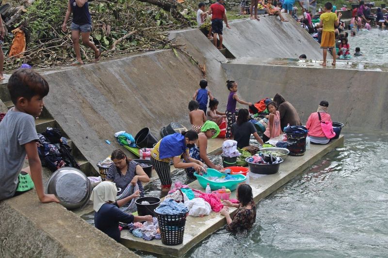 © Reuters. Residents clean their clothes near a river, in Surigao del Norte province, Philippines, December 18, 2021. Philippine Coast Guard/Handout via REUTERS ATTENTION EDITORS - THIS IMAGE HAS BEEN SUPPLIED BY A THIRD PARTY. NO RESALES. NO ARCHIVES. MANDATORY CREDIT