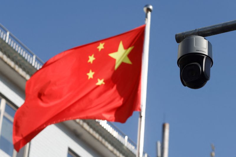 &copy; Reuters. FILE PHOTO: A security surveillance camera overlooking a street is pictured next to a nearby fluttering flag of China in Beijing, China November 25, 2021. REUTERS/Carlos Garcia Rawlins