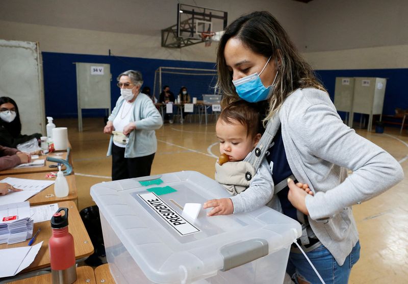 &copy; Reuters. Foto del domingo de una mujer votando con su hijo pequeño en Santiago
Dic 19, 2021. REUTERS/Rodrigo Garrido